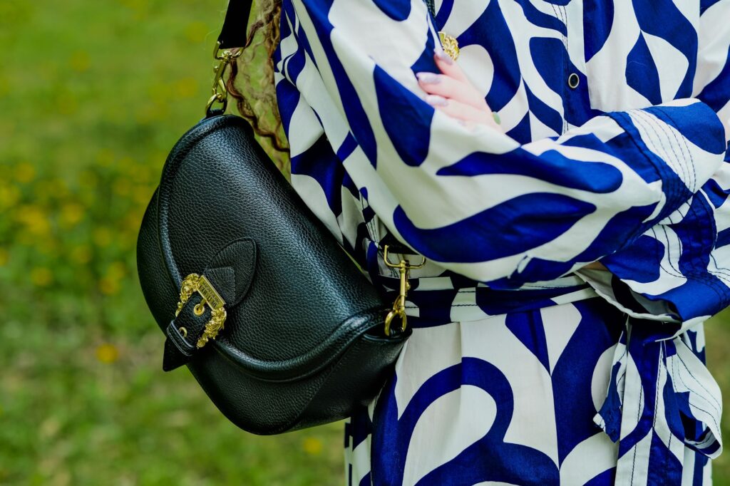 Close-up of a woman wearing a fashionable blue and white outfit with an elegant leather bag.