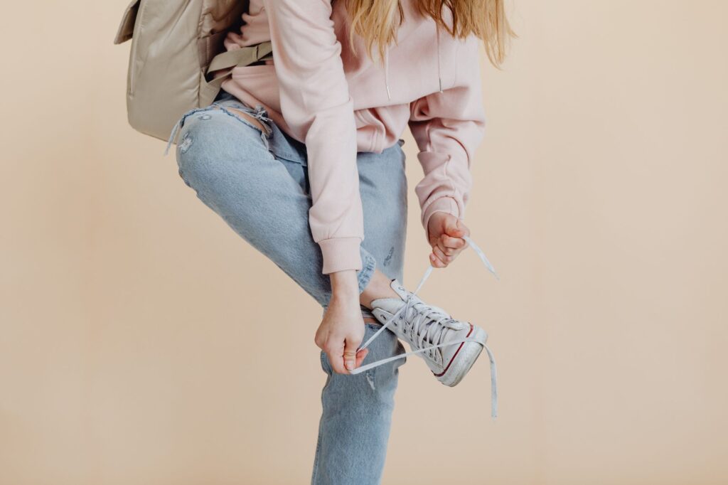 A woman wearing white sneakers with rolled jeans