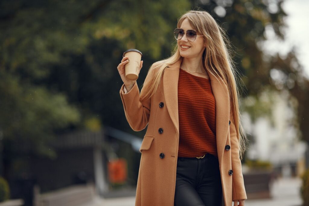 A woman in a camel coat, knit, and ankle boots