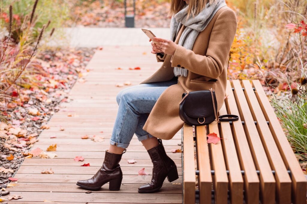 A woman in a cozy fall outfit with a coat and ankle boots