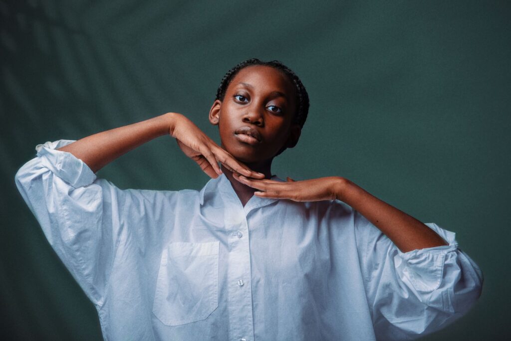 Portrait of a woman in a white shirt posing against a green background.