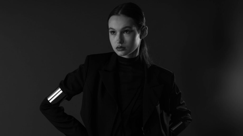 Black and white portrait of a woman in modern fashion with hands on hips.
