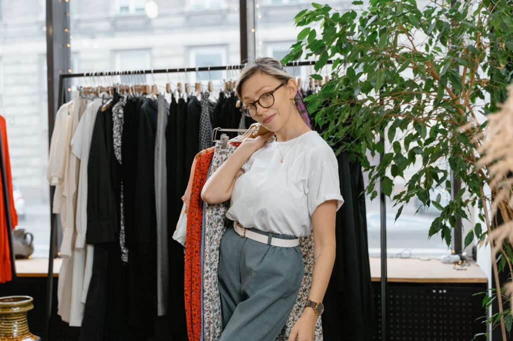 Young woman posing casually in a fashionable boutique with trendy clothing on display.
