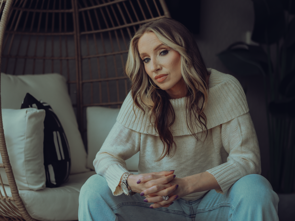 A woman in a camel knit sweater and dark jeans