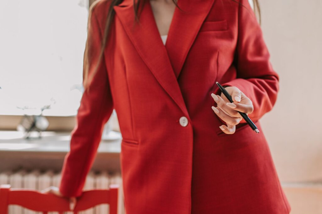 Confident woman in red blazer holding a pen, ready for business leadership.
