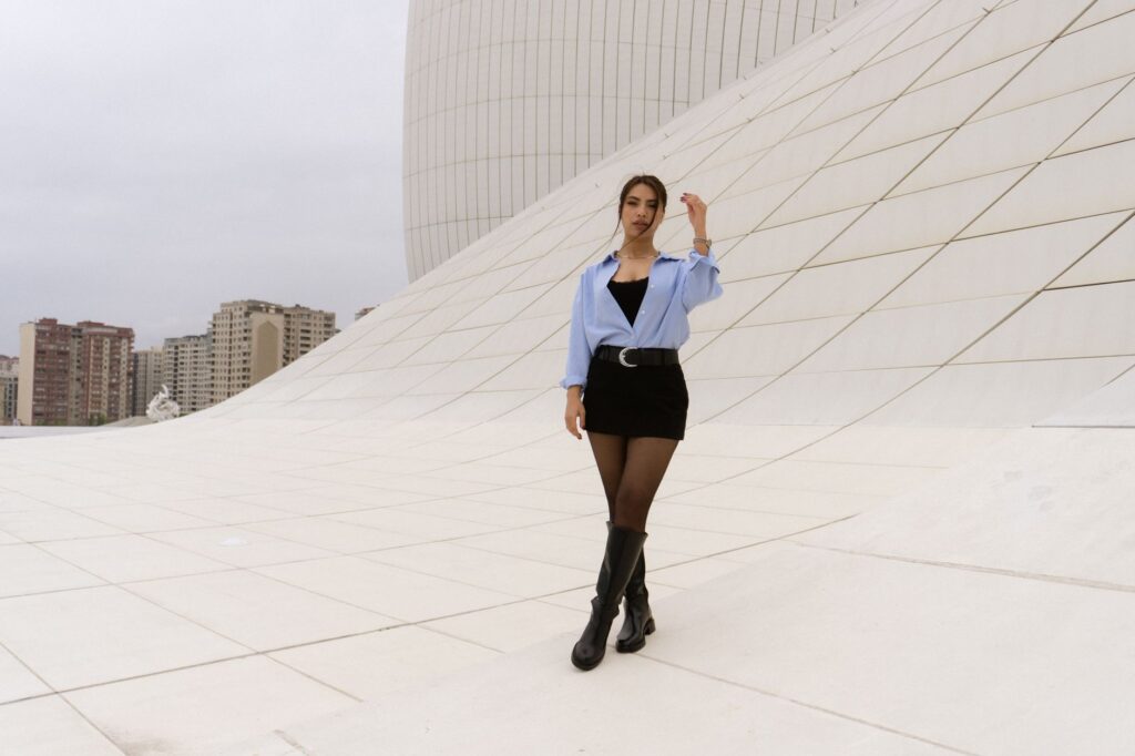 A stylish woman poses against a modern architectural backdrop, showcasing contemporary fashion.