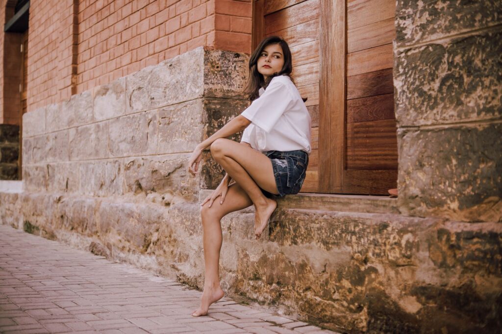 Woman wearing denim bermuda shorts with a cropped top and sneakers