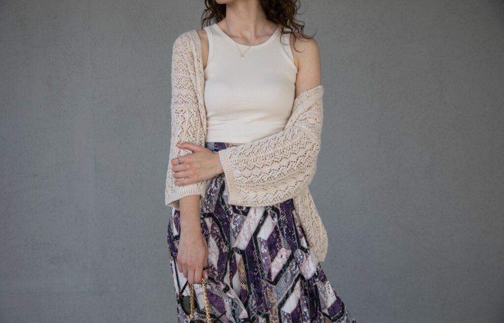 Elegant woman in a knitted cardigan and patterned skirt displaying modern fashion.