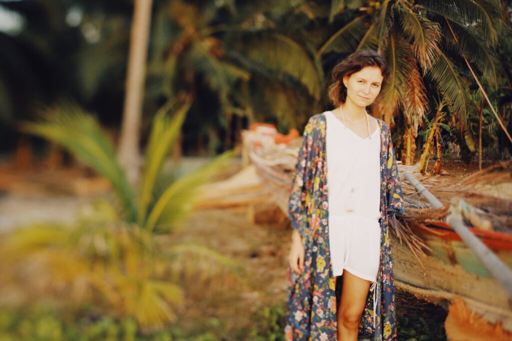 Woman walking on the beach wearing a printed kimono over a swimsuit