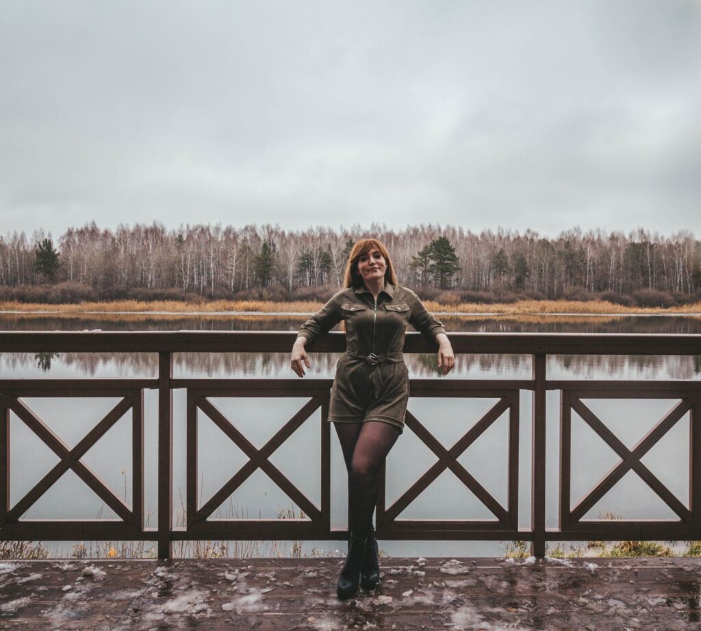 Woman wearing a romper layered with a cardigan and ankle boots for cooler weather