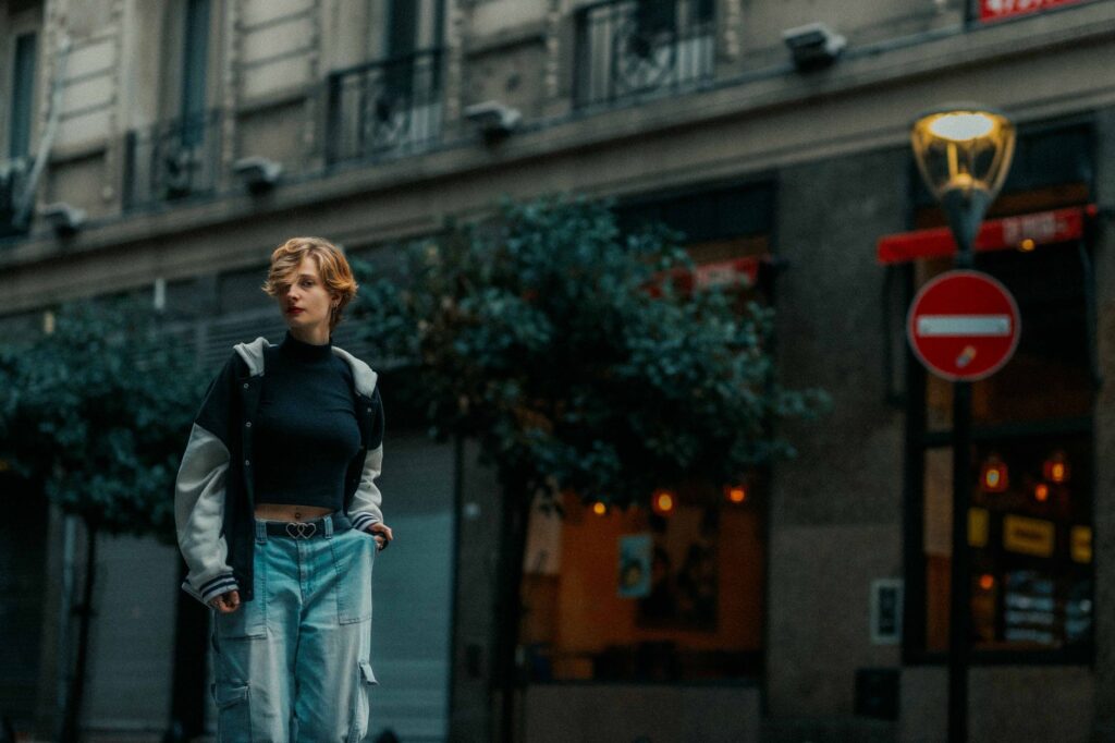A stylish woman in cargo pants walking through a city street at dusk.